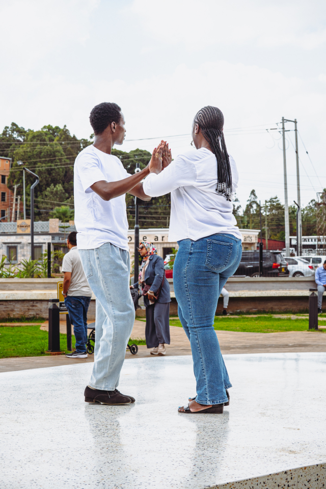 Dancers Facing Each Other on the Plaza Two people in white shirts face each other with raised hands on an outdoor plaza