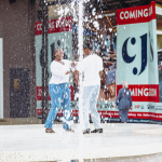 Dancers Performing Through Fountain Spray Two dancers perform on an outdoor stage as a fountain sprays in front of them.