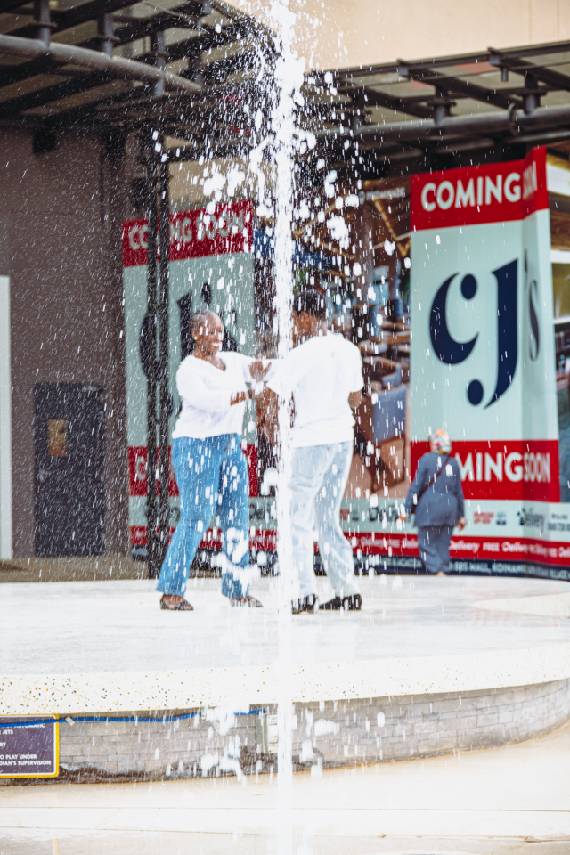 Dancers Performing Through Fountain Spray Two dancers perform on an outdoor stage as a fountain sprays in front of them.